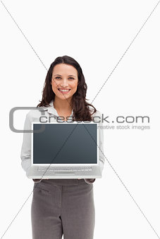 Smiling brunette standing while showing a laptop screen