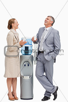 People in suit laughing next to the water dispenser 