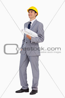 Smiling man in a suit with safety helmet and plans 