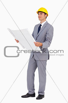 Good-looking man in a suit with safety helmet and plans 