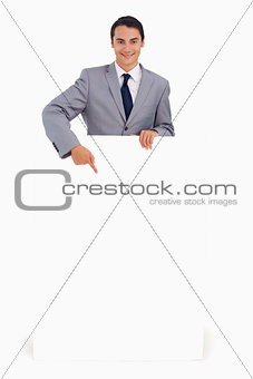 Good-looking man holding and pointing a big poster