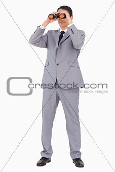 Businessman smiling while using binoculars 