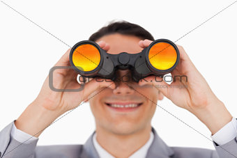 Close-up of a smiling businessman using binoculars 