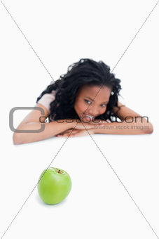 A green apple with a smiling girl in the background