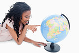 A young girl is pointing at a globe