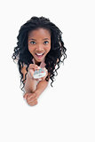 A surprised young woman is pointing a television remote at the c