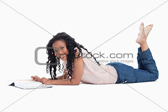 A woman lying on the floor smiling at the camera with a magazine