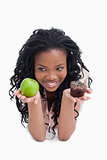 A smiling young woman is holding an apple and a bun on the palms