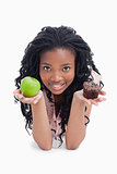 A young woman looking at the camera is holding an apple and a bu