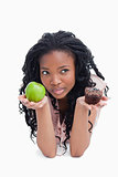 A woman holding an apple and a bun on her palms is thinking