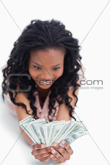 An excited young woman is holding American dollars in her hands