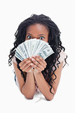 A woman is holding American dollars up to her face