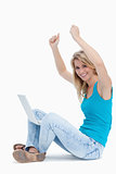 Smiling woman has her arms in the air with a laptop between her 