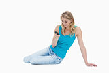 A smiling woman is sitting on the floor holding her mobile phone