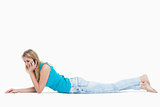 A happy woman lying on the floor is talking on her mobile phone