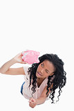 A young woman lying on the ground is looking inside a piggy bank