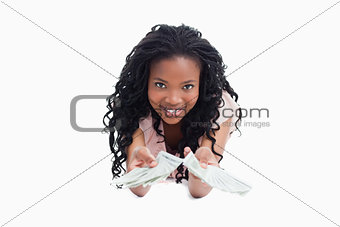 A smiling young woman is holding American dollars out in front o
