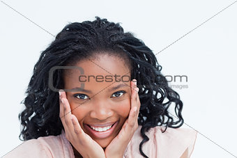 Head shot of a smiling young woman holding her head in her hands