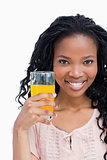 Close up of a smiling young woman holding a glass on orange juic
