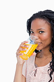 A girl looking at the camera is drinking orange juice
