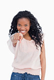 A smiling young woman is pointing a finger at the camera