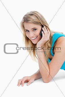 A smiling woman looking at the camera is talking on her mobile p