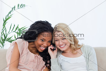 Two women are listening to a mobile phone  