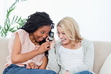 A laughing woman is holding a mobile phone up to her friends ear
