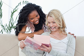 Two smiling women look at a present inside a pink box