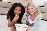 Two women lying on the ground with a bowl of popcorn