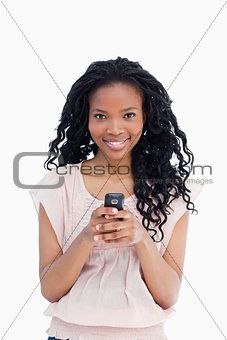 A beautiful woman looking at the camera is holding a mobile phon