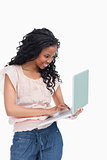 A happy young woman is typing on the laptop she is holding
