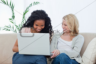 Two women with a laptop in front of them are laughing