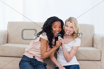 Two women are holding a microphone 