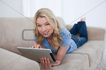 A woman holding a tablet is looking at the camera