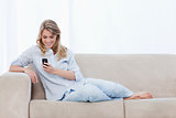 A woman sitting on a couch is holding a mobile phone