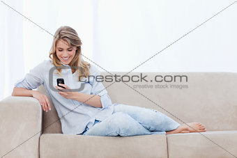 A woman sitting on a couch is holding a mobile phone
