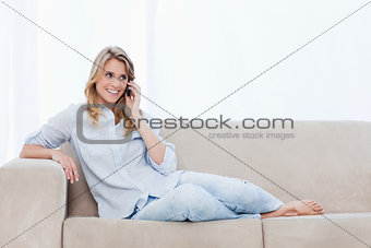 A woman on a couch is talking on her mobile phone