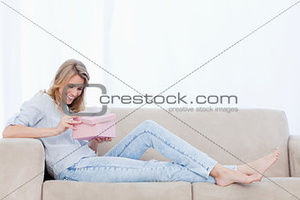 A happy woman looks at a present inside a pink box