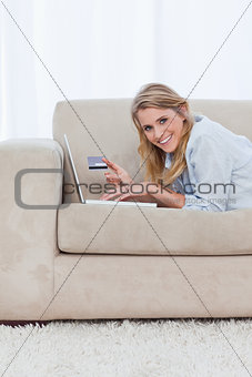 A woman with a laptop is looking at the camera and holding a ban