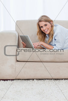 A woman smiling at the camera is holding a tablet