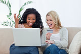 Two laughing women with a laptop and a bank card