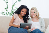 Two women smiling at the camera with a tablet computer in front 