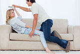 A man tries to get the television remote control off his girlfri
