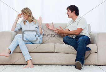 A man is having an argument with his girlfriend while sitting on