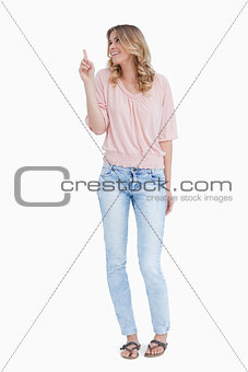 A smiling woman is pointing upwards