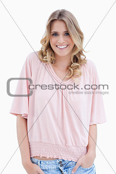 A woman with her arms in her pocket is smiling at the camera