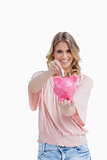 Smiling woman putting money in a piggy bank that she is holding