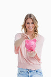 Woman holding a piggy bank is putting money into it