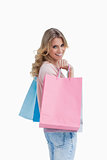 A woman carrying shopping bags is smiling at the camera